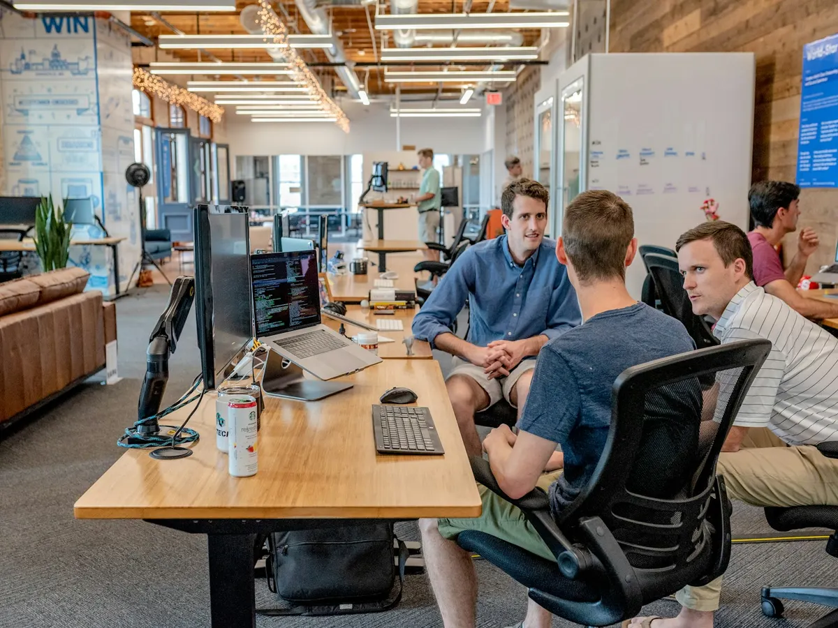 Colleagues talking at their desks in an open-plan office